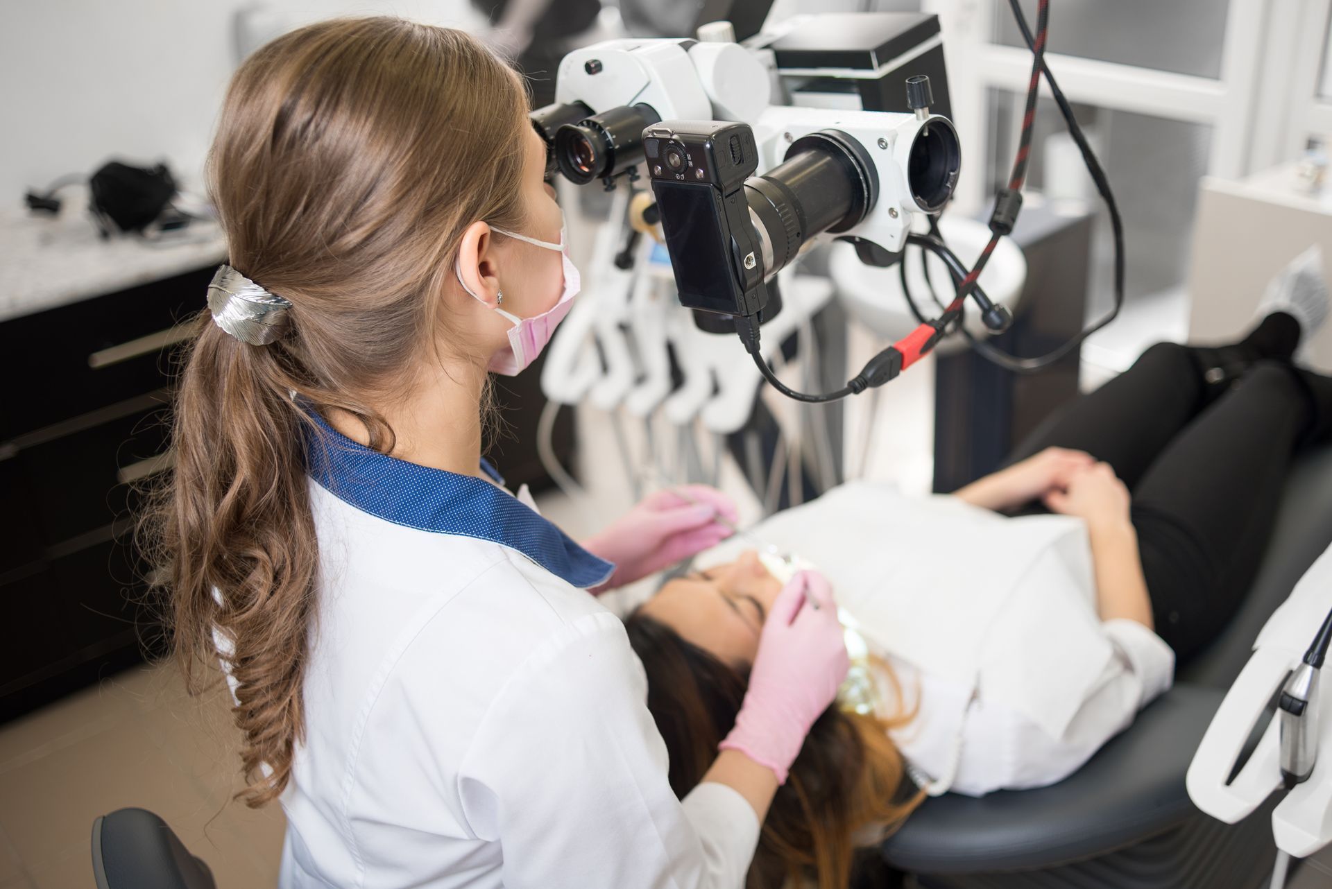 Dentist examining a patient in a dental chair with imaging equipment overhead