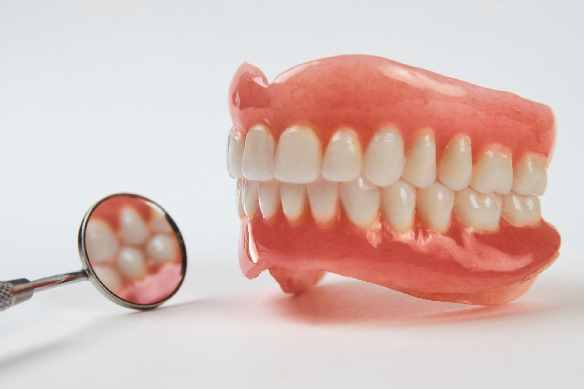 Pink dental dentures with a magnifying glass showing the teeth close-up