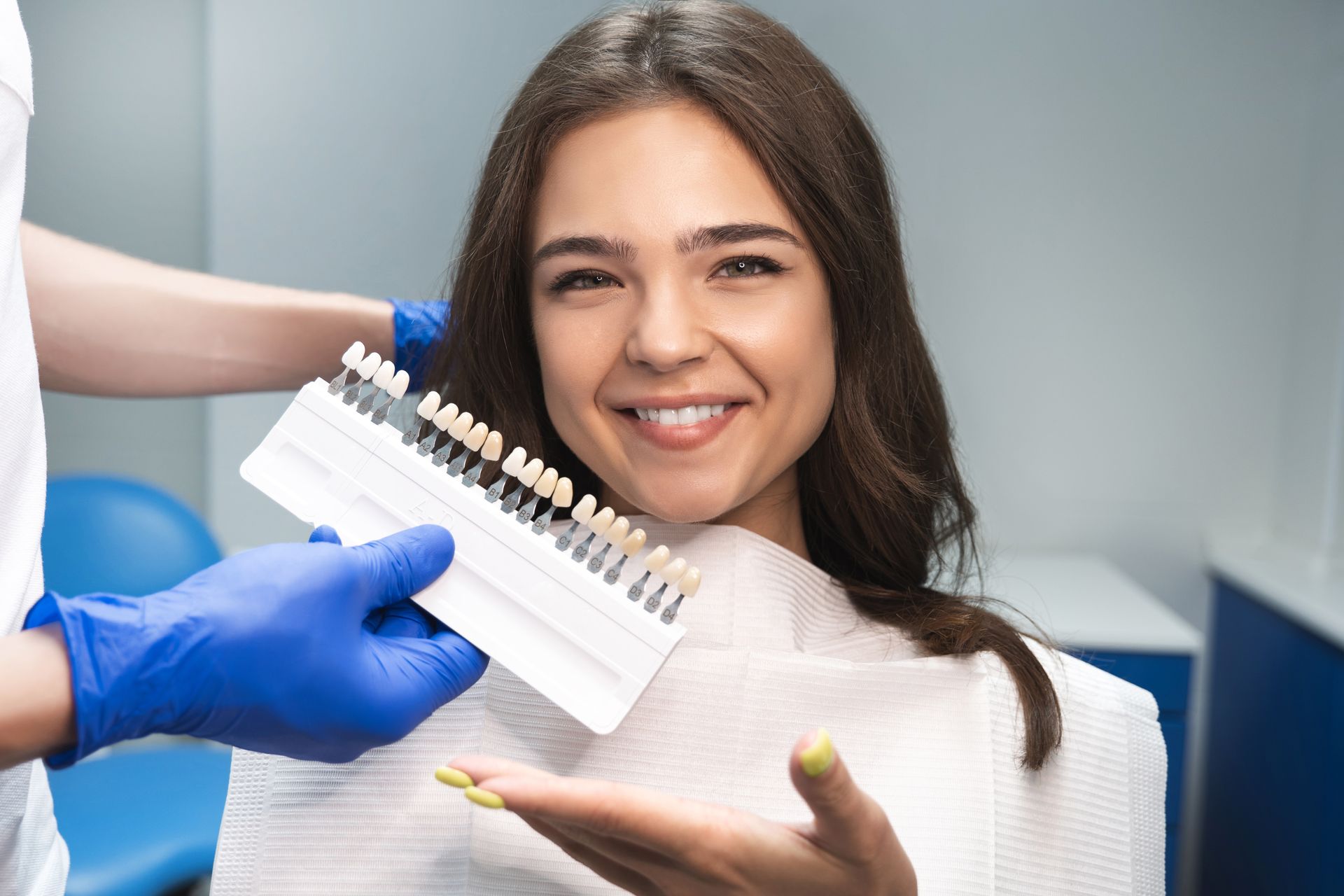 Dentist showing tooth shade guide to smiling patient in a clinic