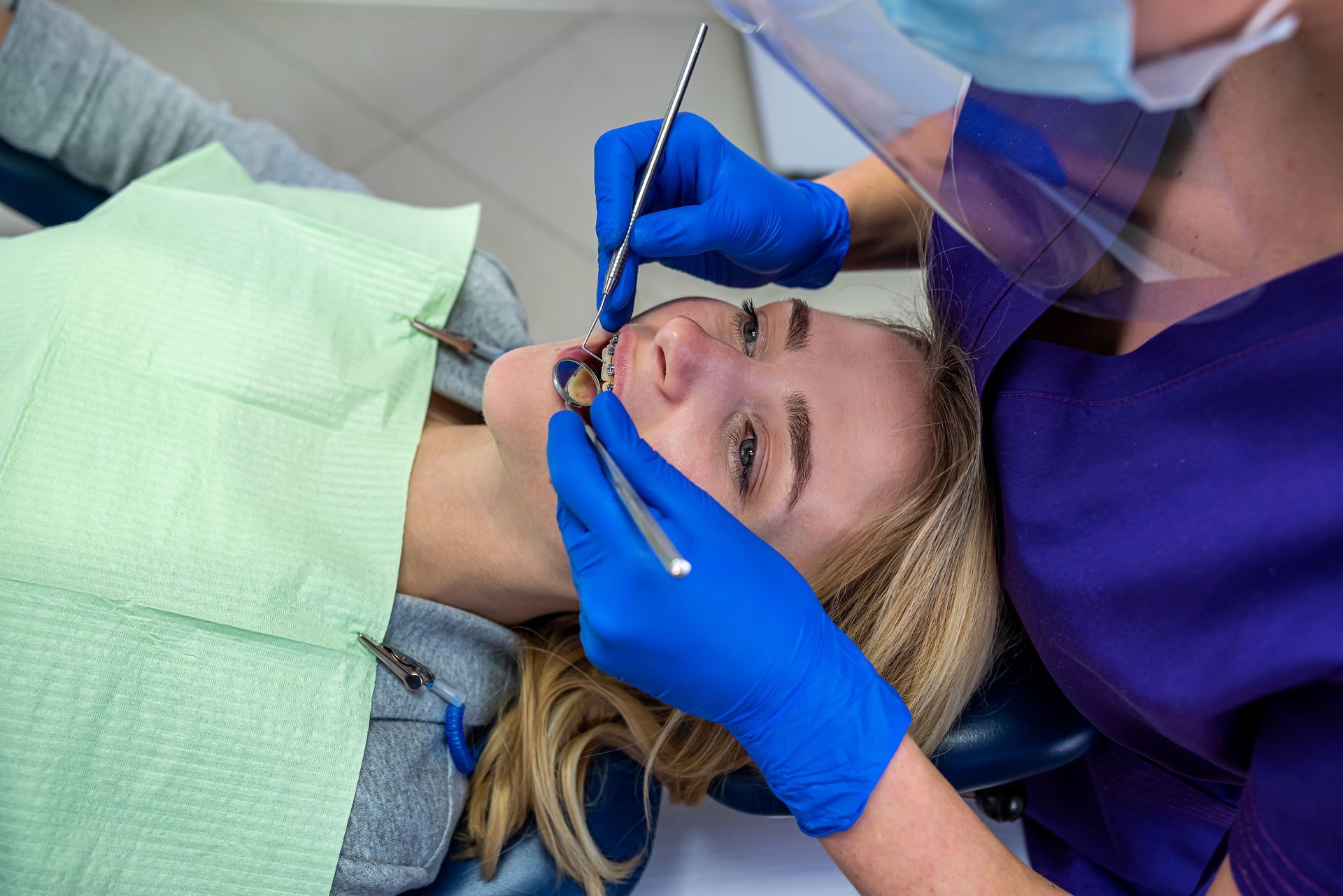 Dentist adjusting a patient’s braces with blue gloves in a clinical setting