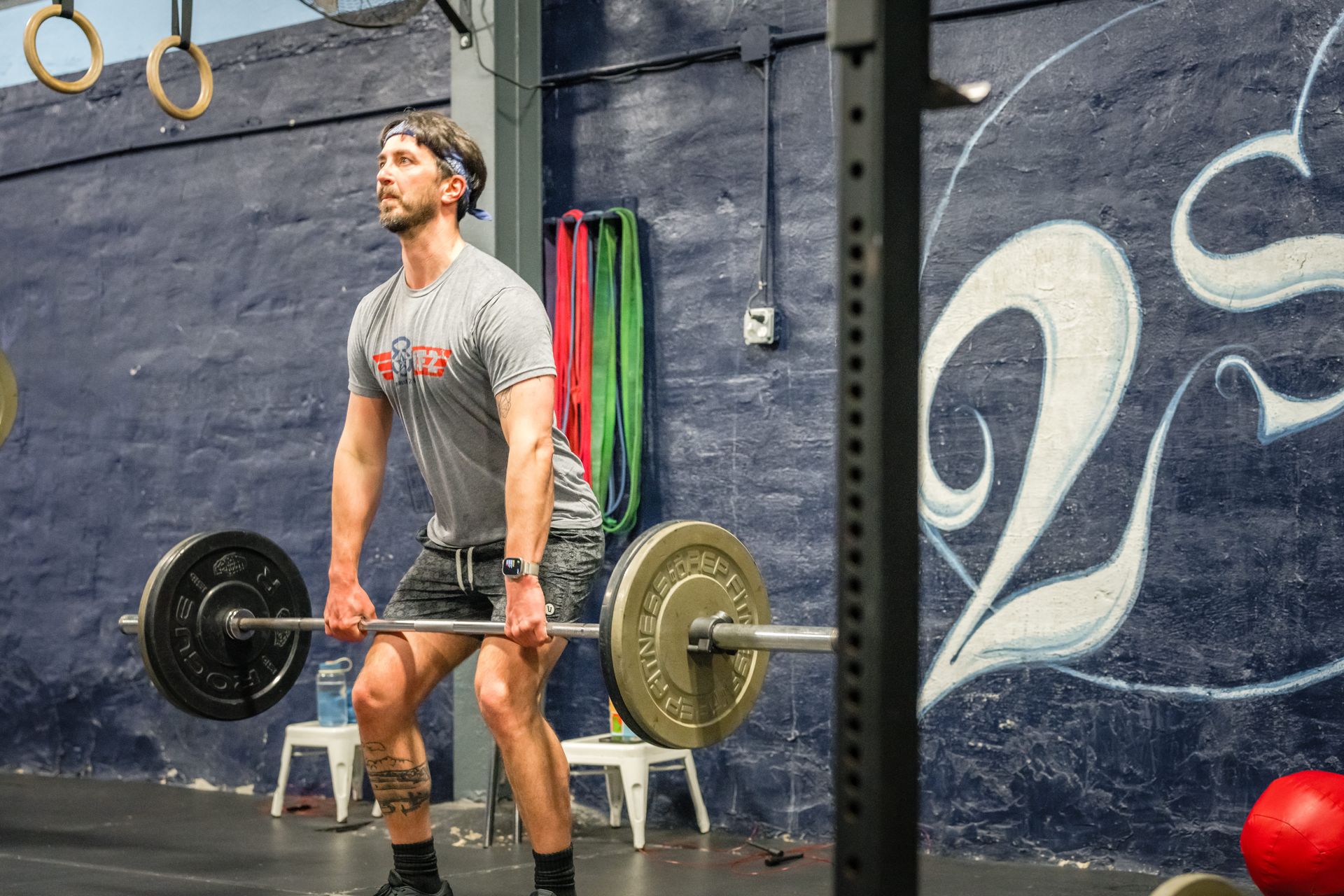 A man is lifting a barbell in a gym.