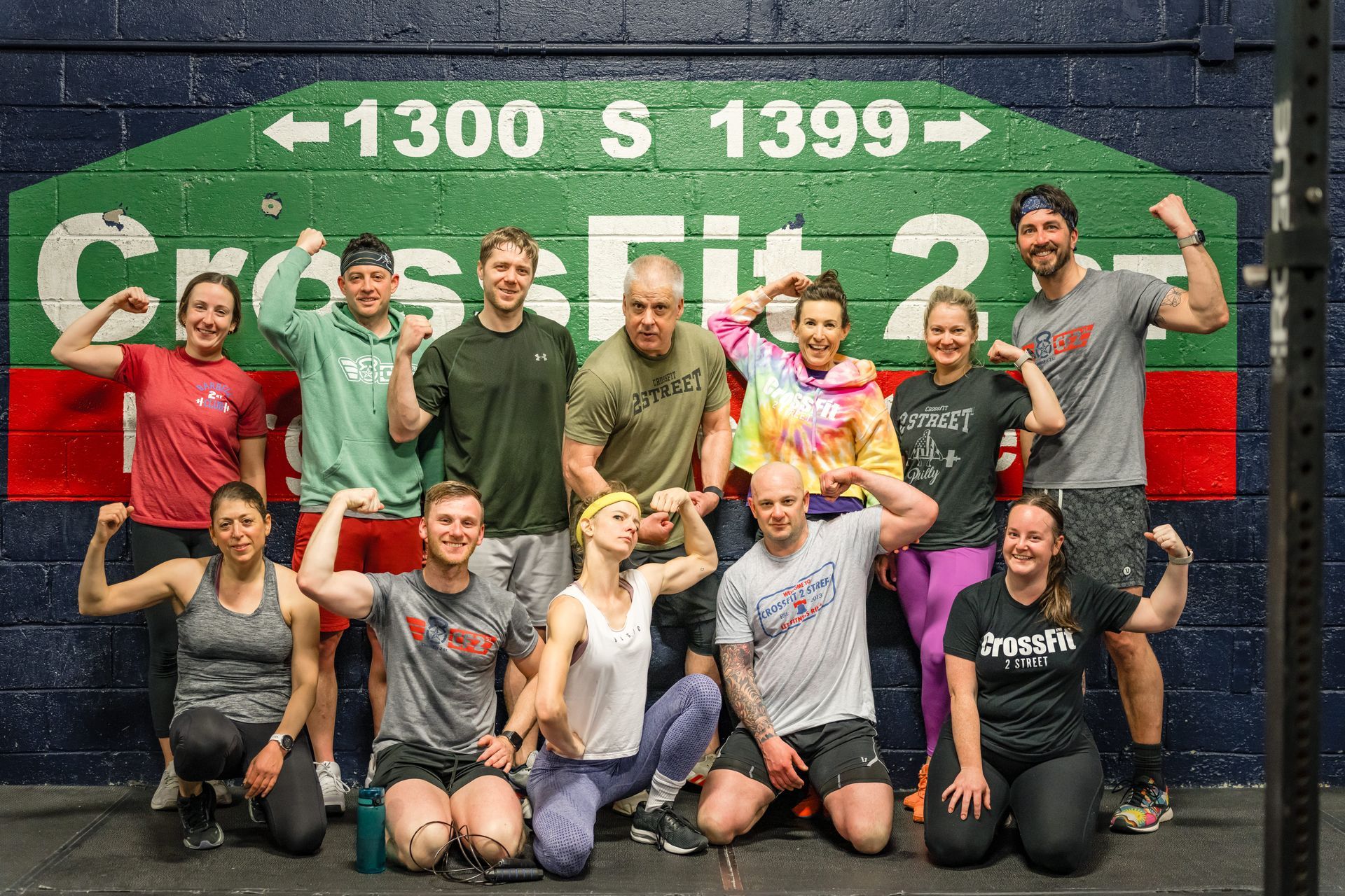 A group of people are posing for a picture in front of a sign that says crossfit 2.