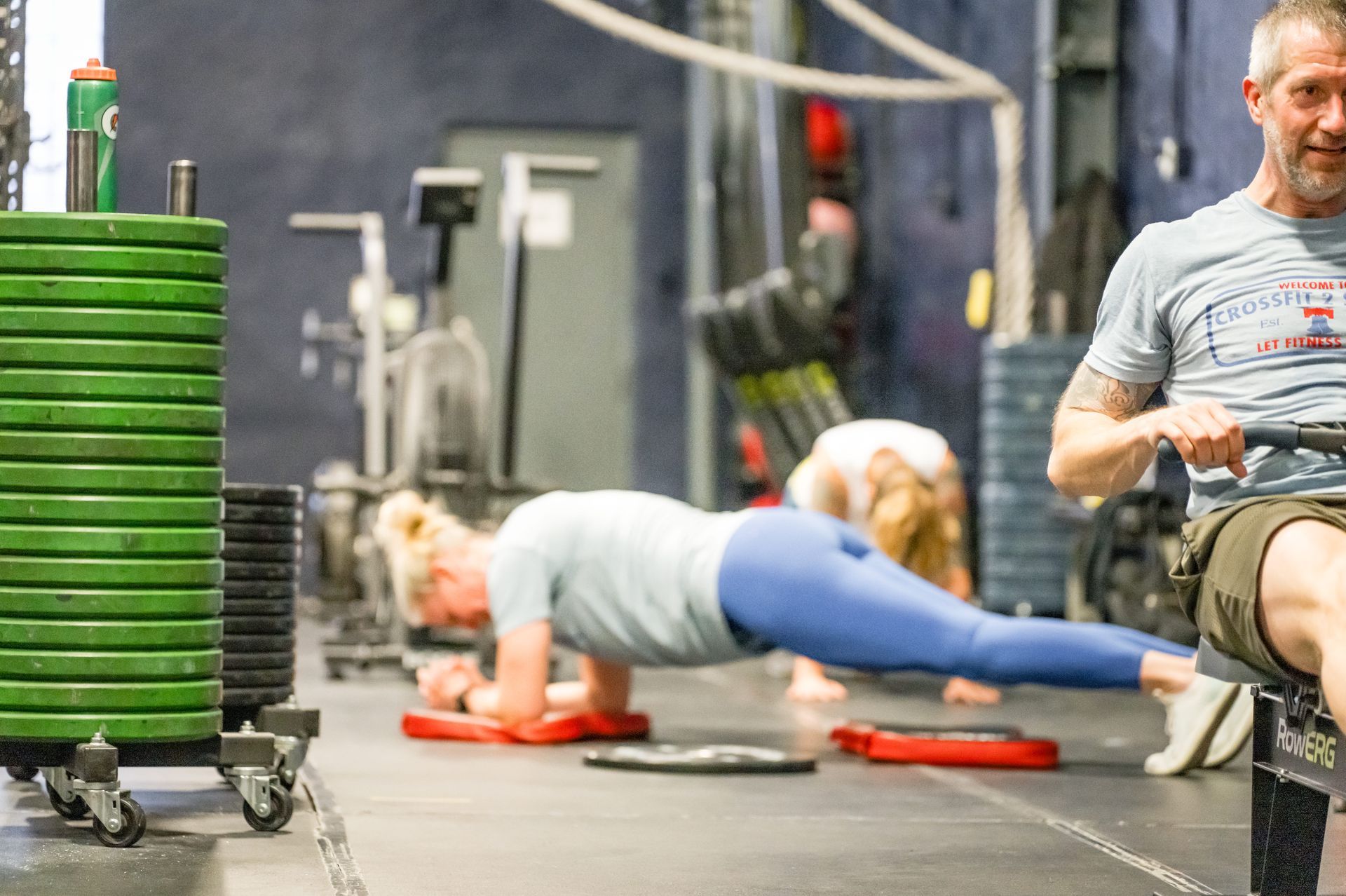 A man and a woman are doing push ups in a gym.
