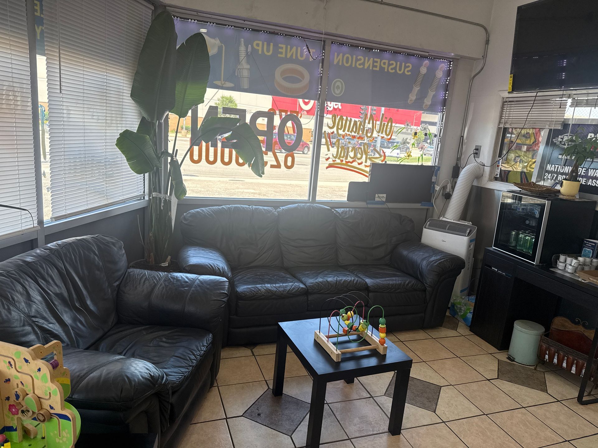 Black leather couches in a storefront lounge with a coffee table and large window signage.