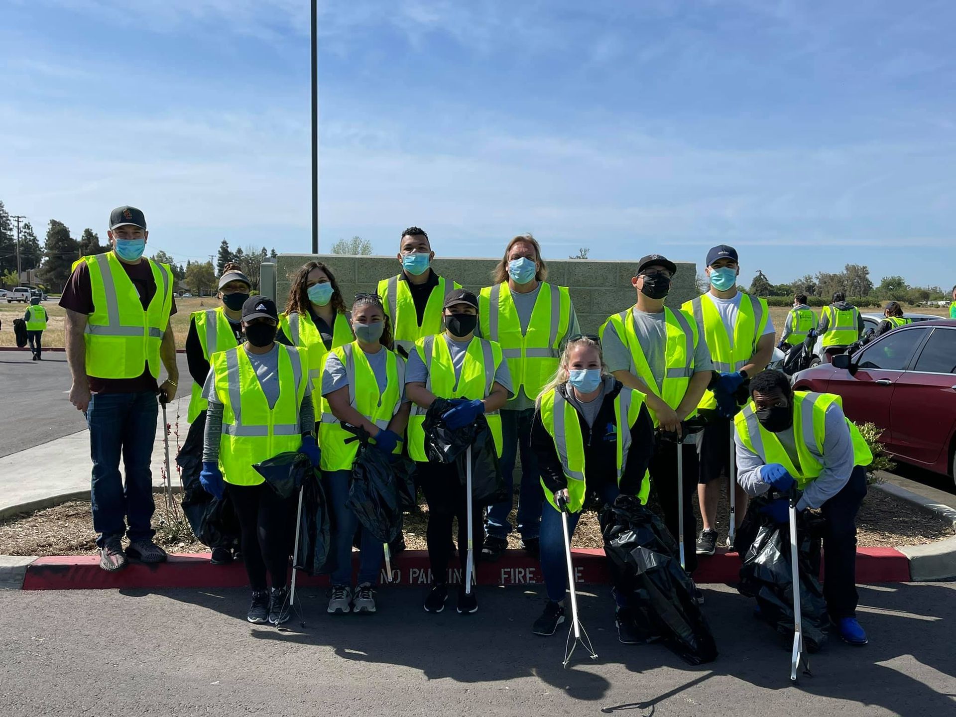 A group of people wearing yellow vests and masks are posing for a picture.