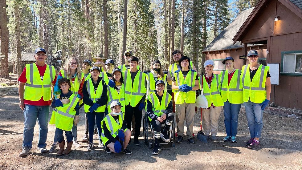 A group of people are posing for a picture in front of a cabin in the woods.