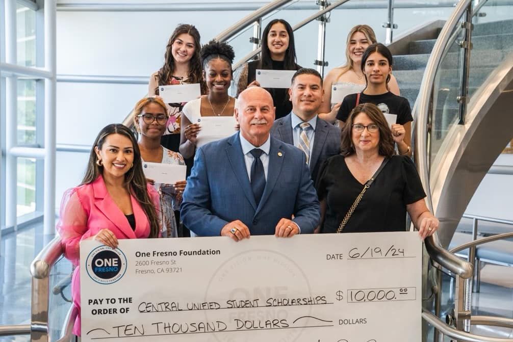 A group of people are standing on a staircase holding a large check.