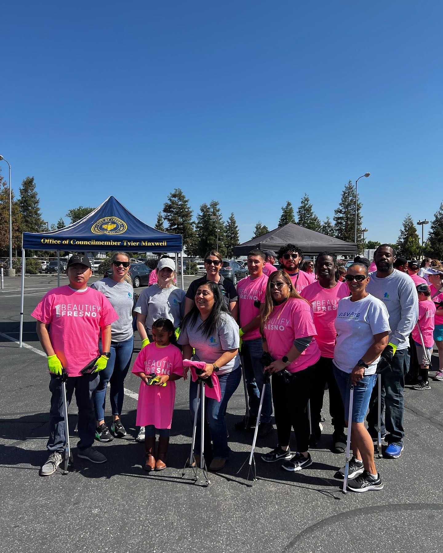 A group of people wearing pink shirts are standing in a parking lot.