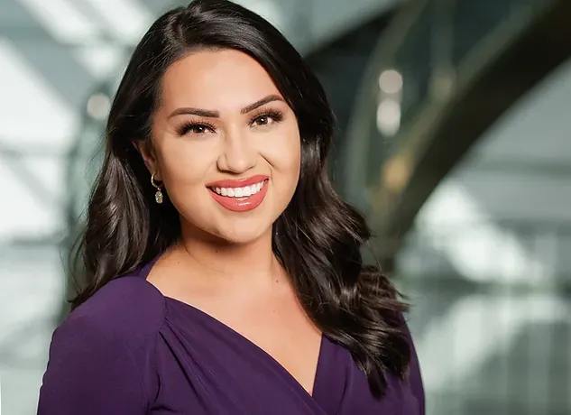 A woman in a purple dress is smiling for the camera.