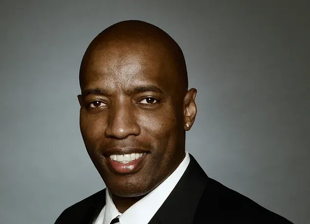 A man in a suit and tie is smiling for the camera