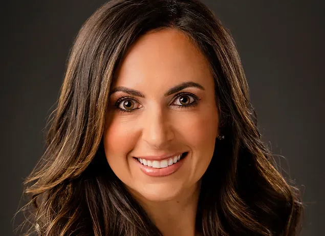 A woman with long brown hair is smiling for the camera.