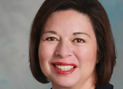 A woman with short brown hair and red lips is smiling for the camera.