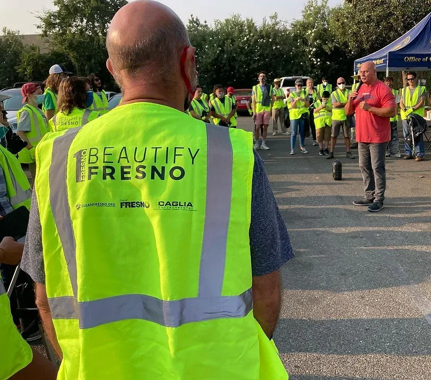 A man wearing a yellow vest that says beautify fresno