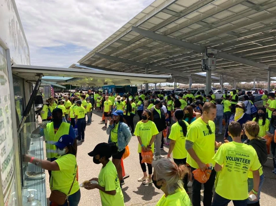 A large group of people wearing neon yellow shirts are standing in a parking lot.