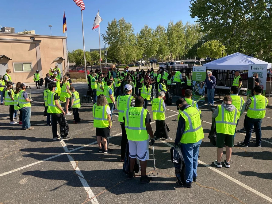 A group of people wearing yellow vests are standing in a parking lot.