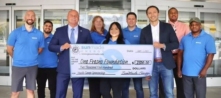 A group of people standing next to each other holding a large check.