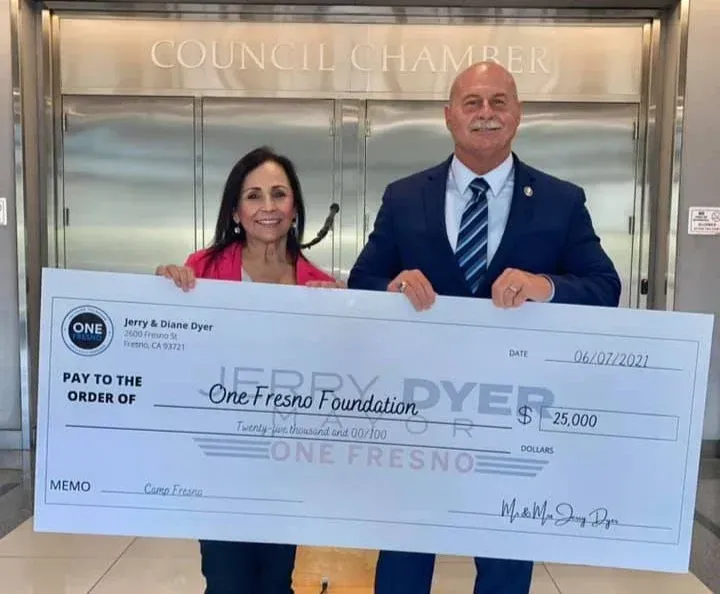A man and a woman holding a large check for the jerry dyer one fresno foundation