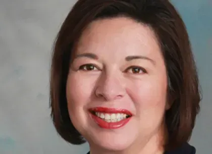 A woman with short brown hair and red lips is smiling for the camera.