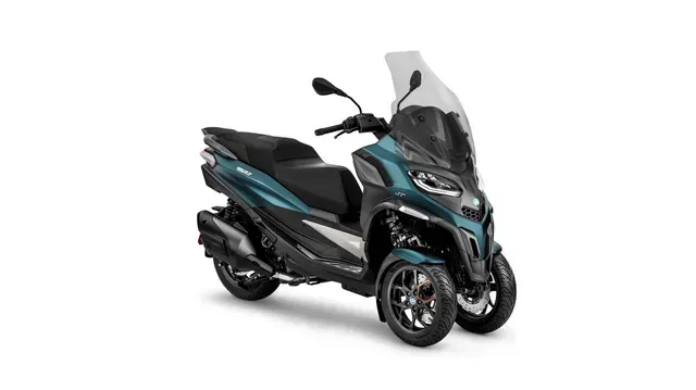 Scooter a tre ruote nero e verde acqua, con parabrezza, inclinato su sfondo bianco