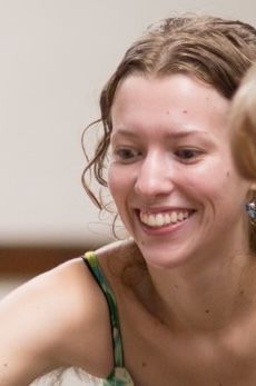 Smiling young woman with fair skin and curly brown hair.