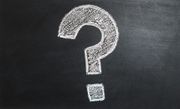 A white, hand-drawn question mark on a black chalkboard background.