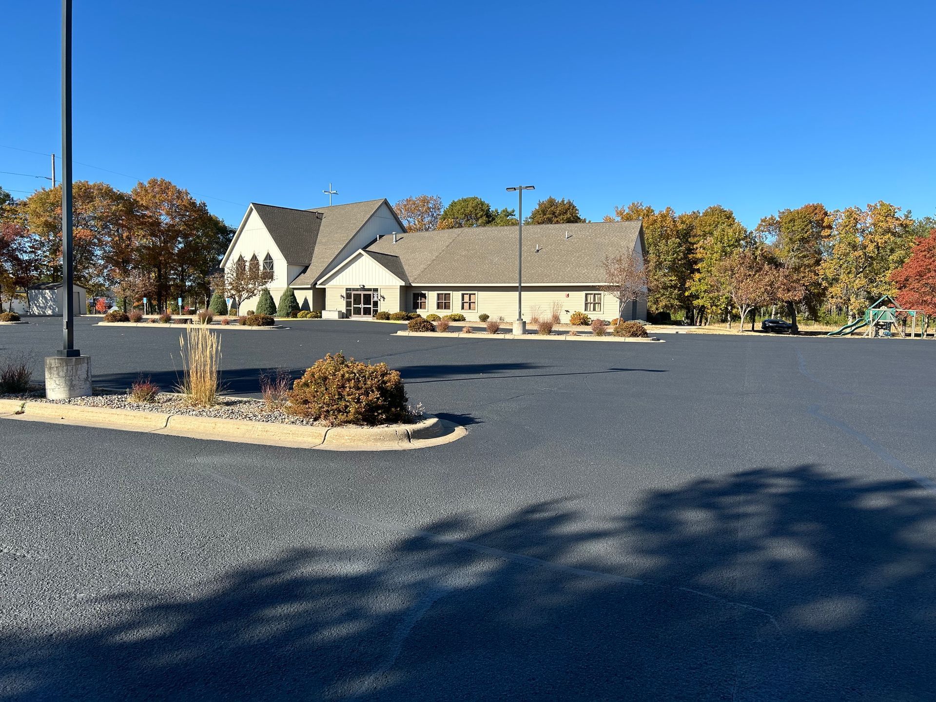 A church with a parking lot in front of it on a sunny day.