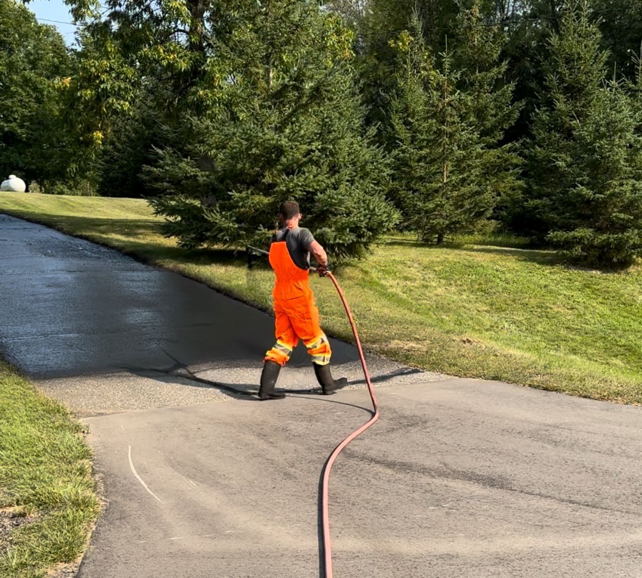 A man is cleaning a driveway with a hose.