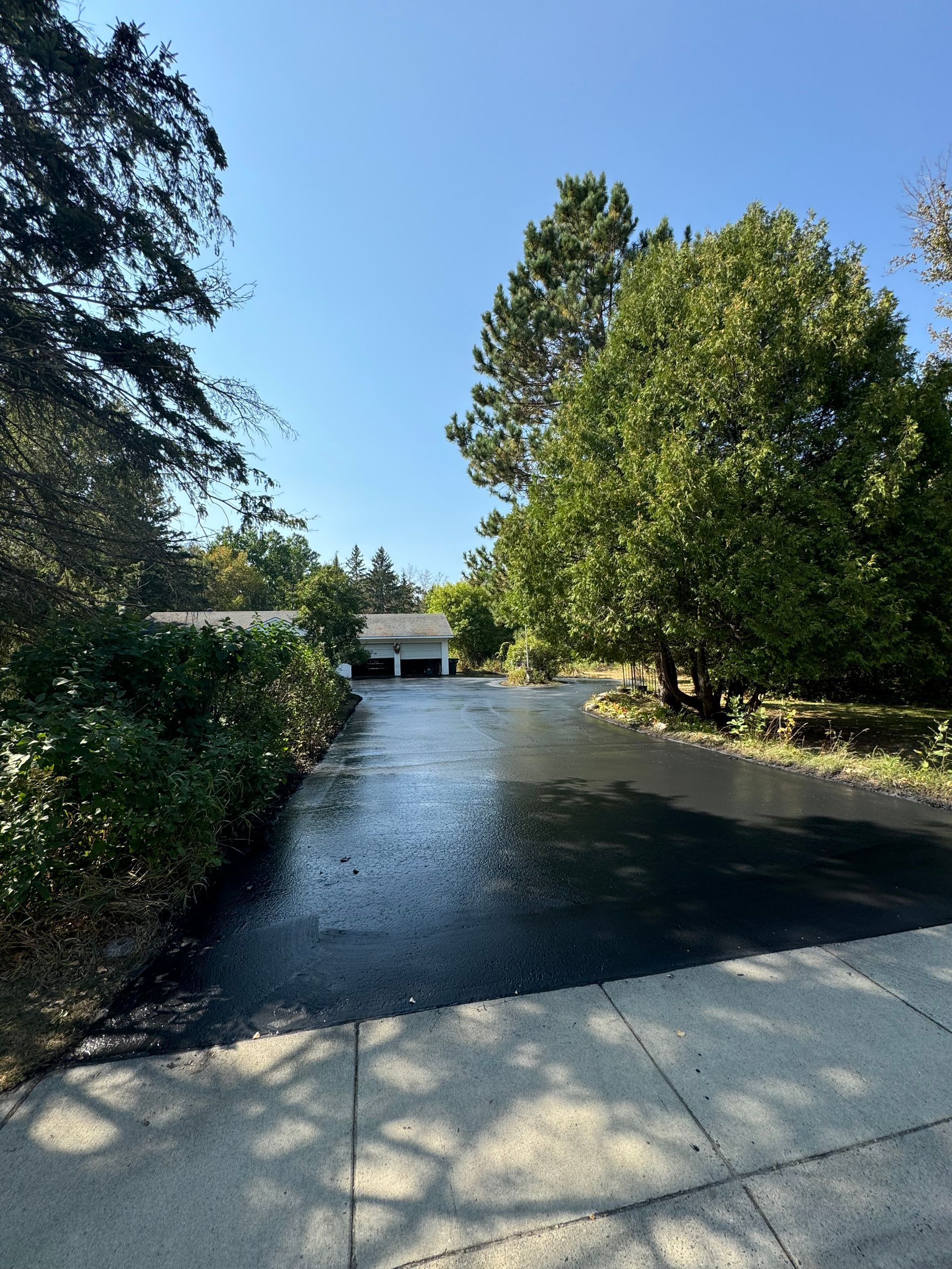 A road with trees on the side of it and a house in the background