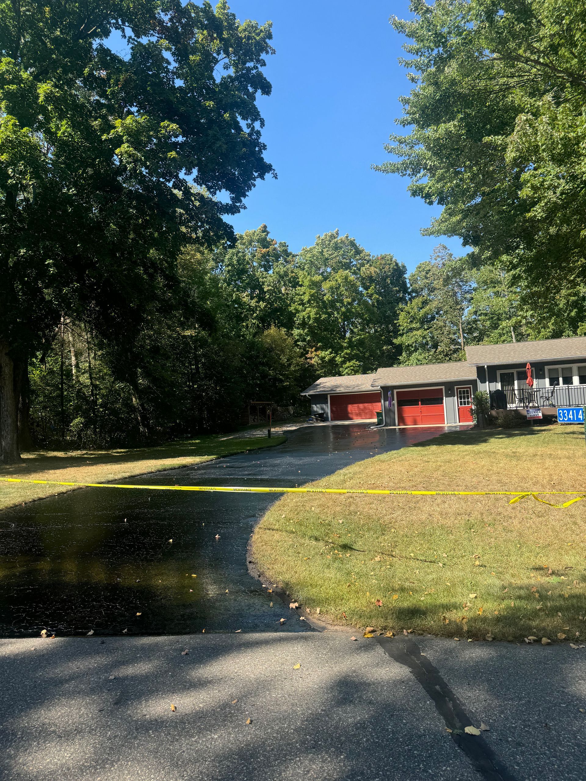 A house with a red garage door is surrounded by trees and a driveway.