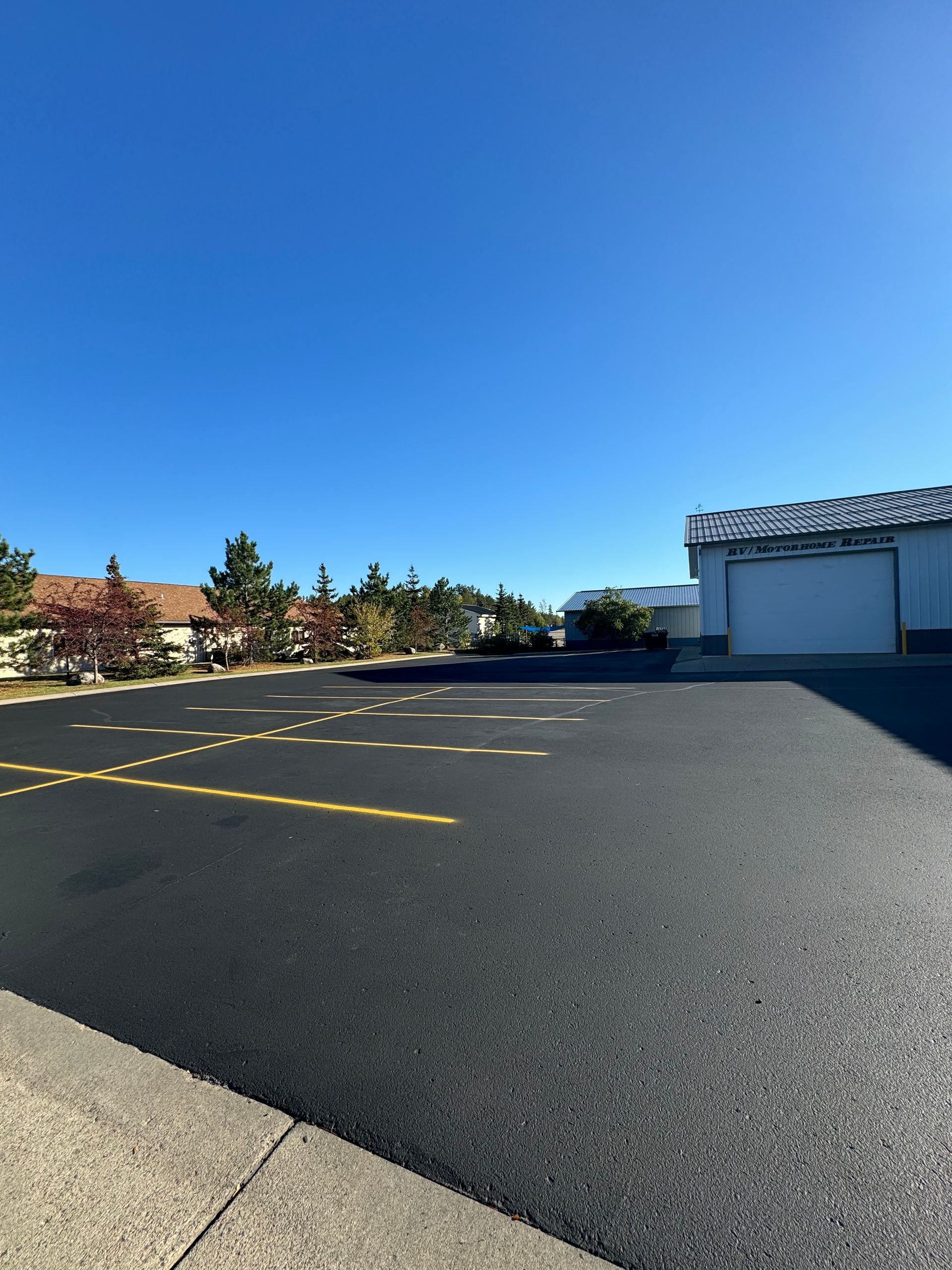 A parking lot with a garage in the background on a sunny day