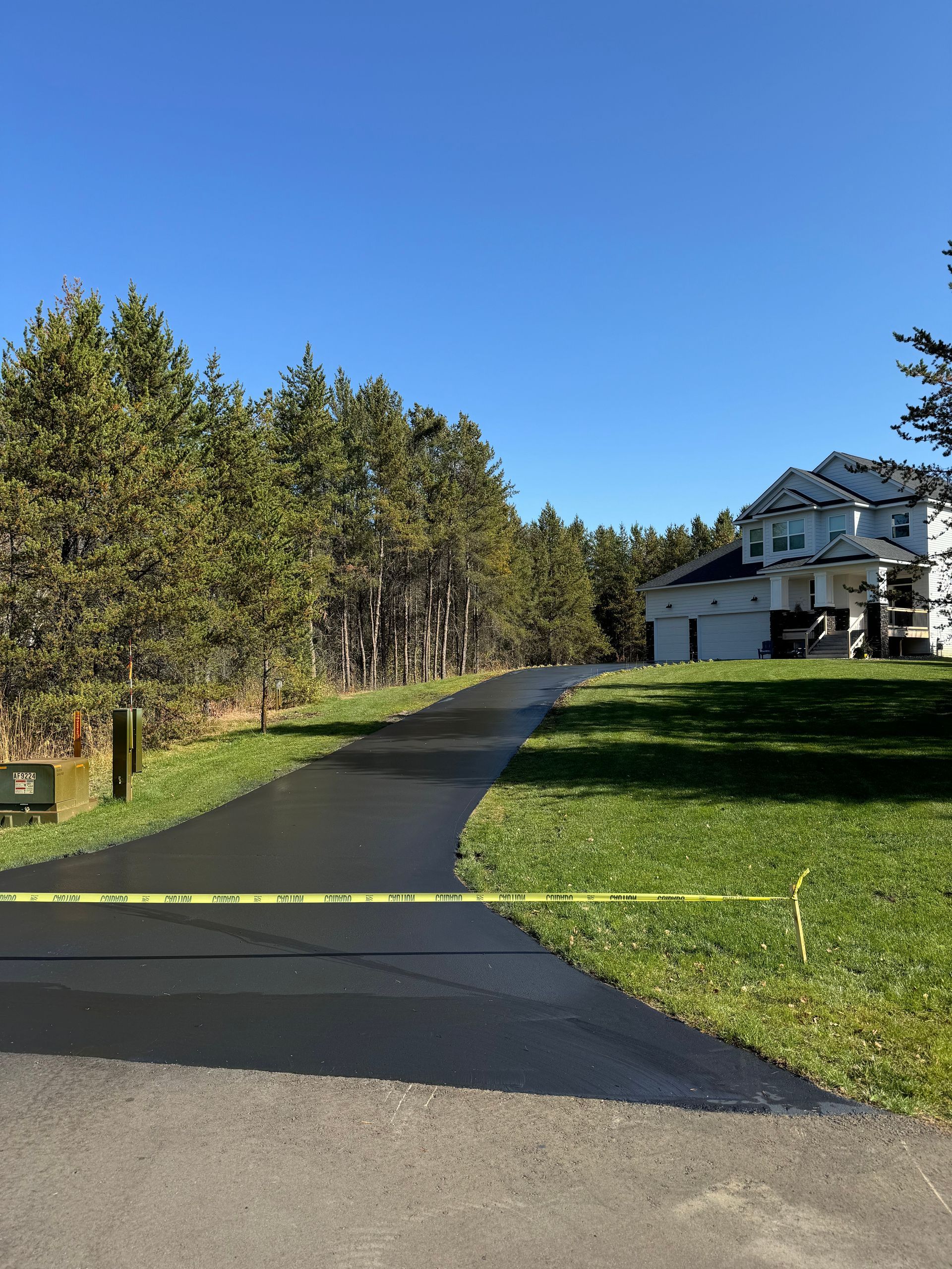 A driveway leading to a house with a yellow tape on it.
