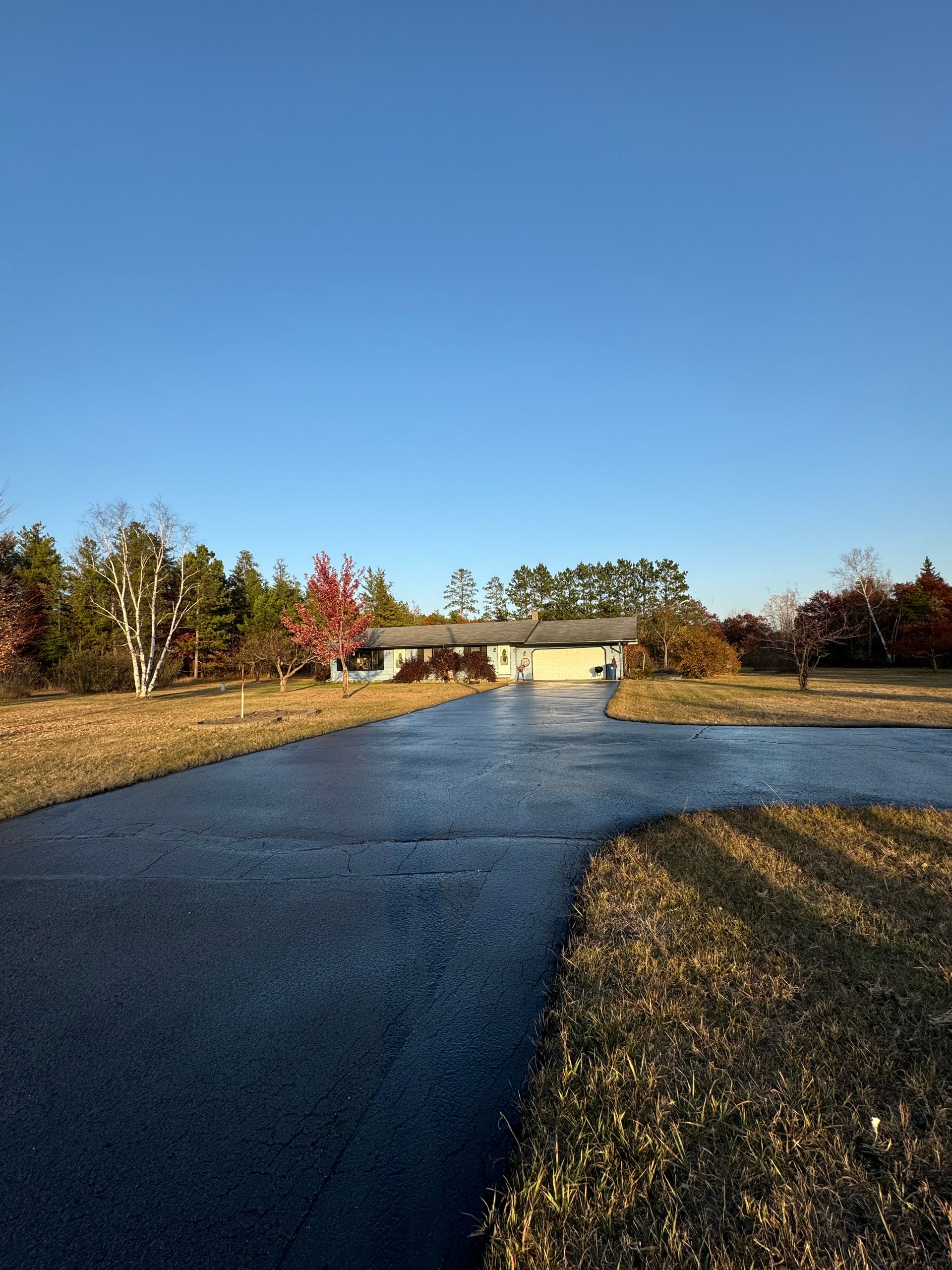 A driveway leading to a house in the middle of a field.