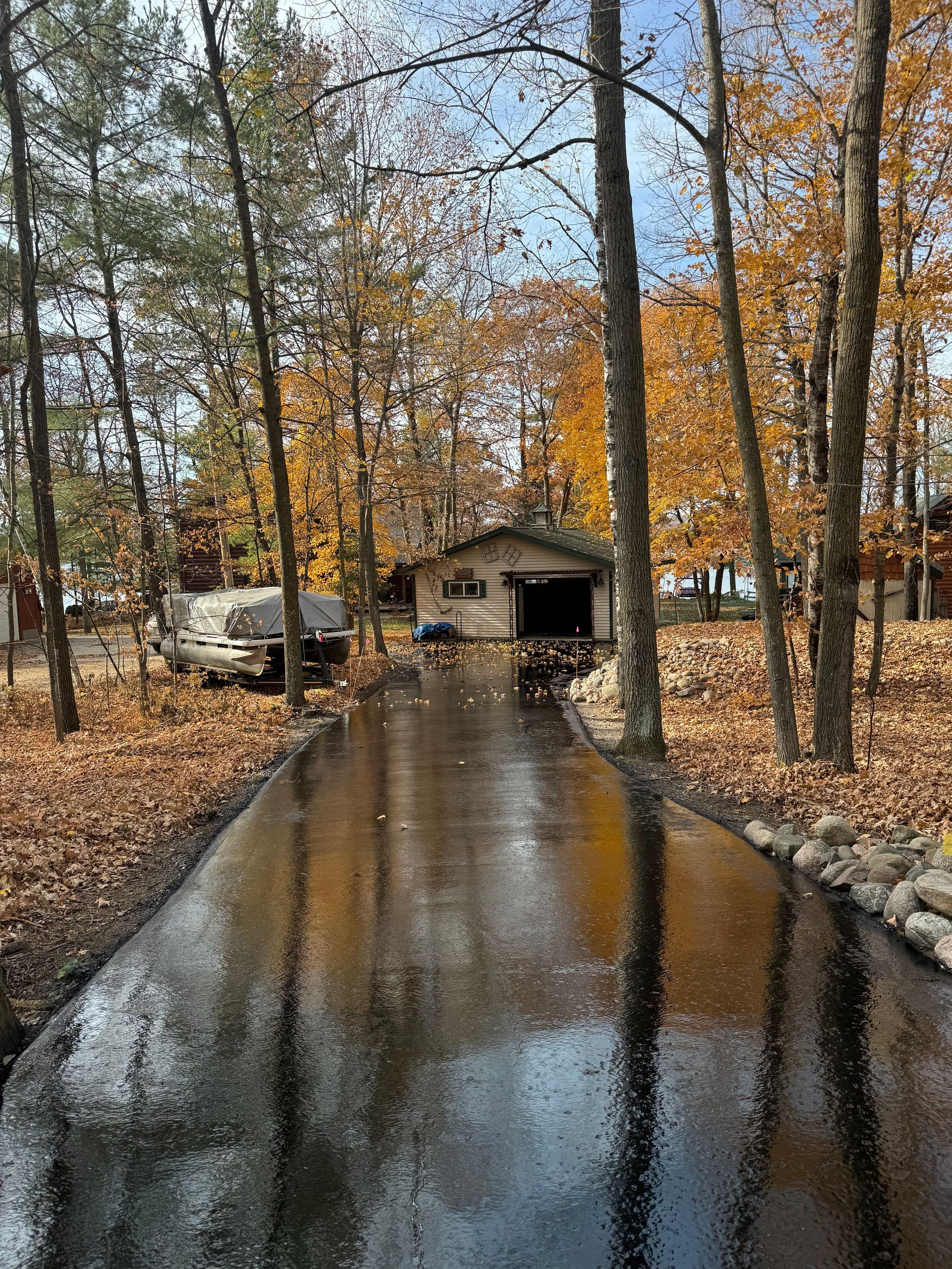 A driveway leading to a house in the woods on a rainy day.