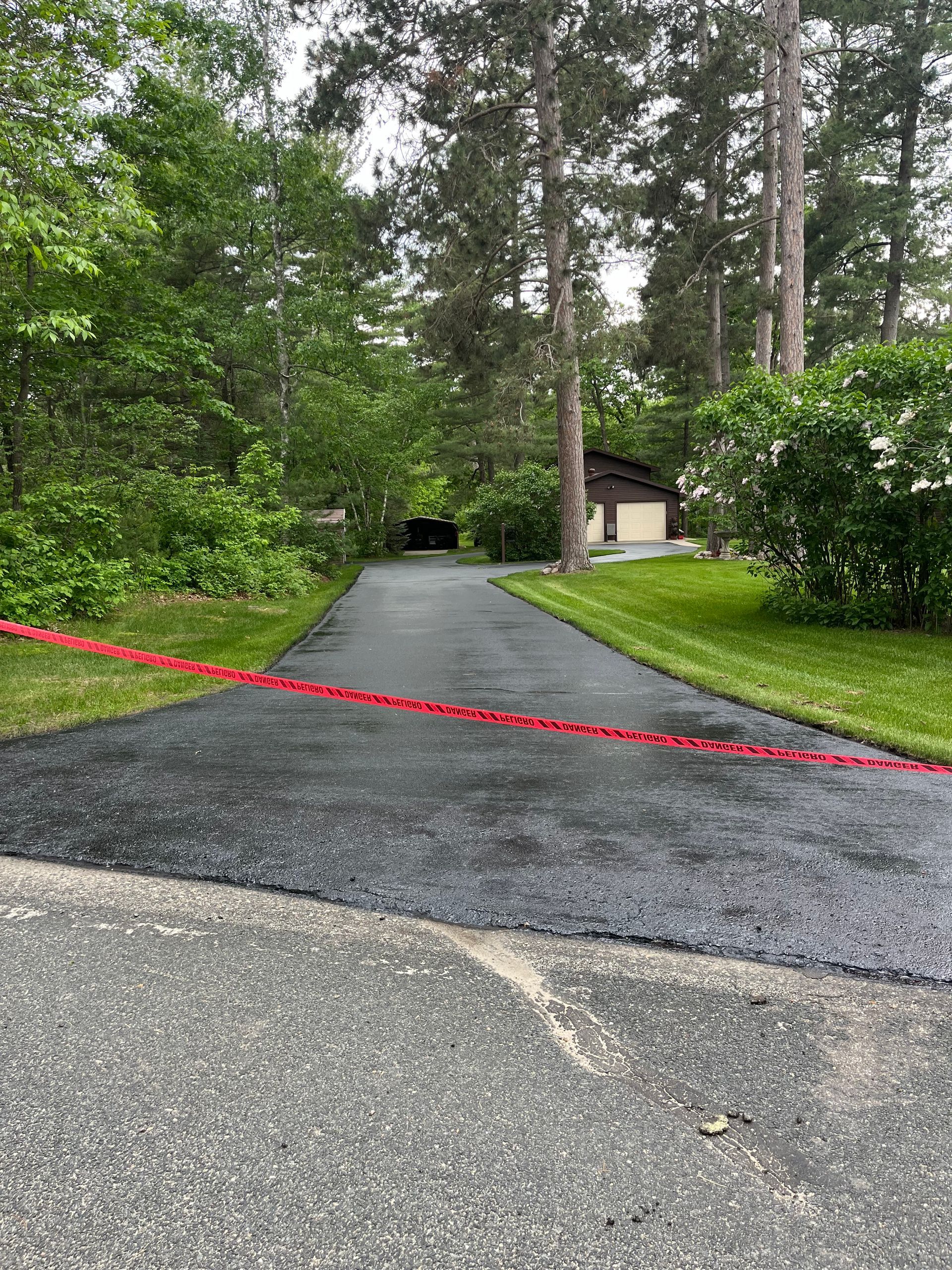 A driveway leading to a house surrounded by trees and grass.