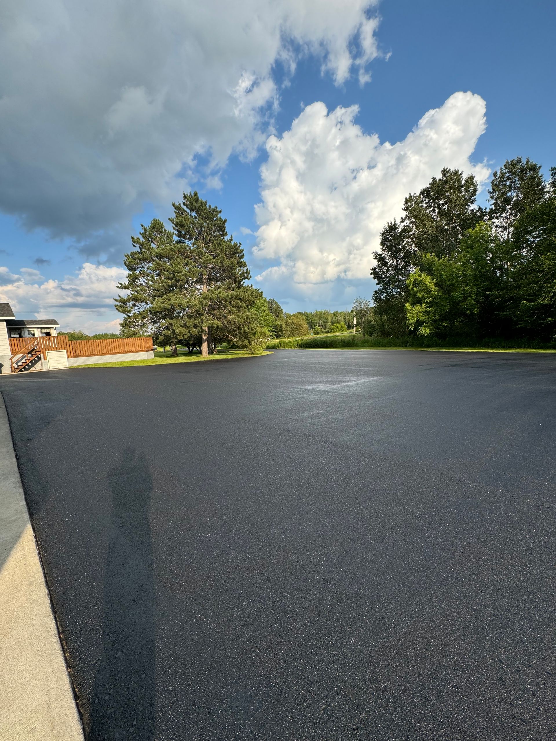 A large empty parking lot with trees in the background