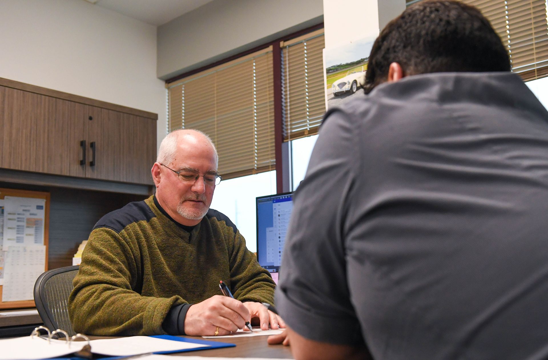 Engineer working on a project at a desk with a client sitting across from him.