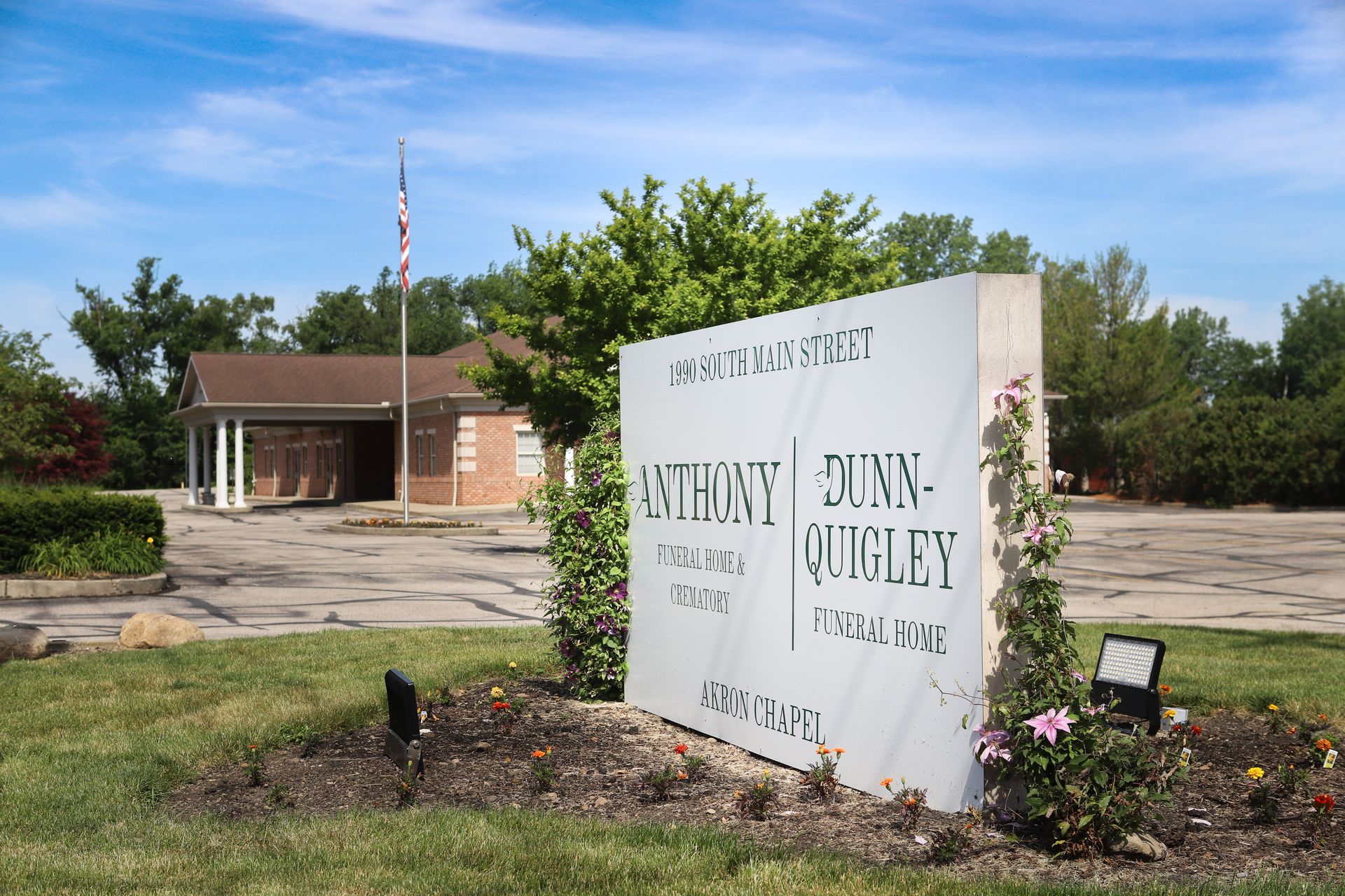 Brick building with covered entrance, small blue car parked out front, green lawn.