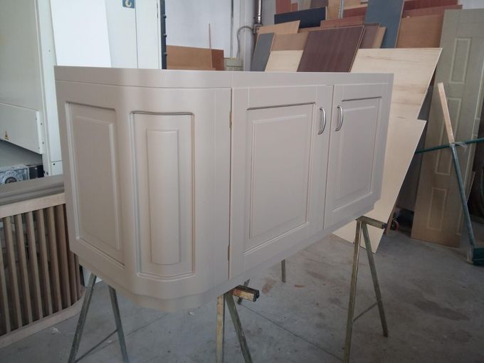 Cassettiera in legno con quattro cassetti, sormontata da una pila di scatole marroni, su uno sfondo blu.