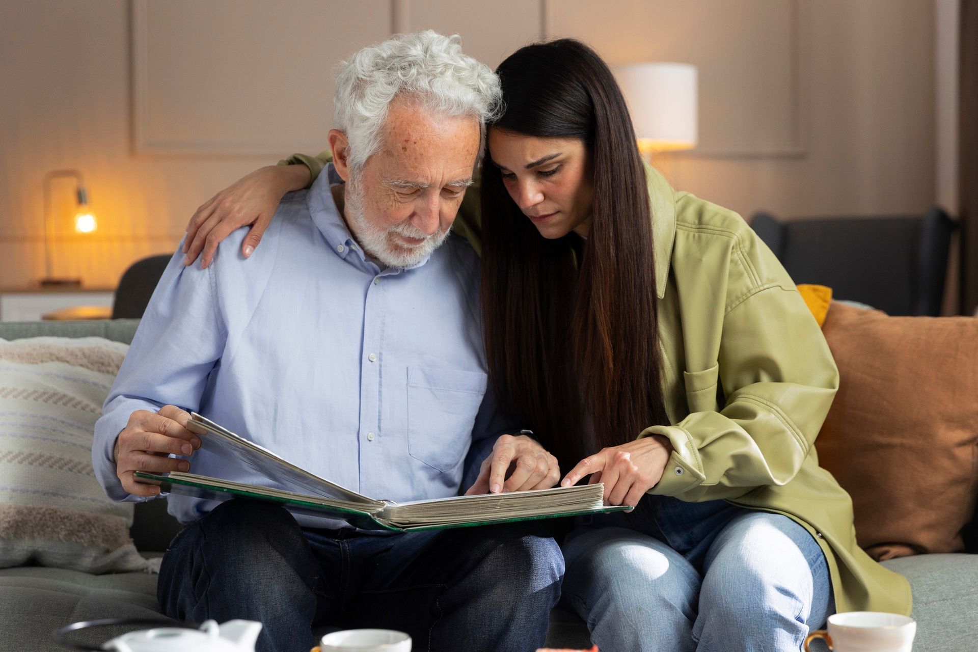 Two people sitting on a couch looking at a photo album in a cozy living room