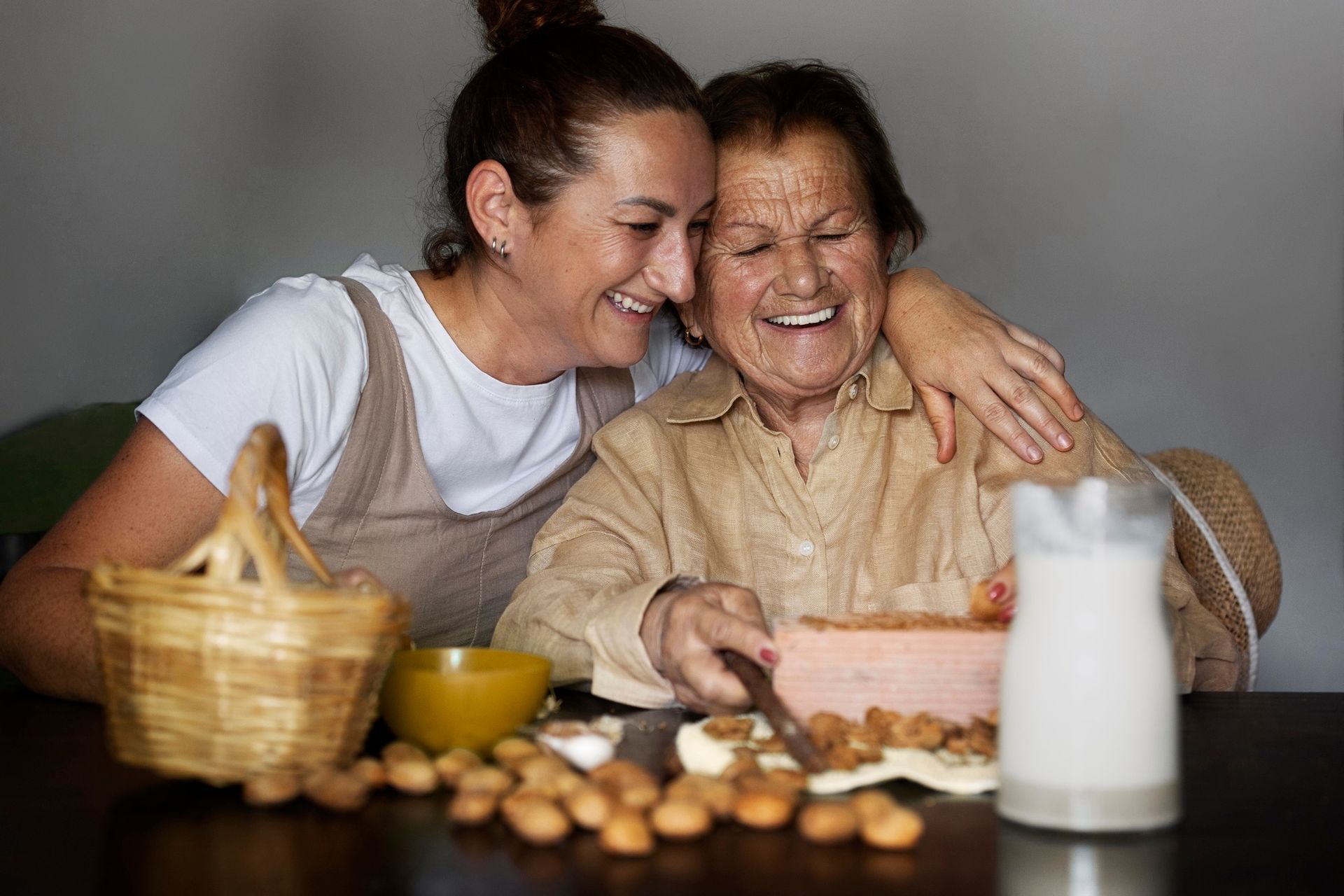 Two smiling people embrace at a table with bread, eggs, and a bottle of milk
