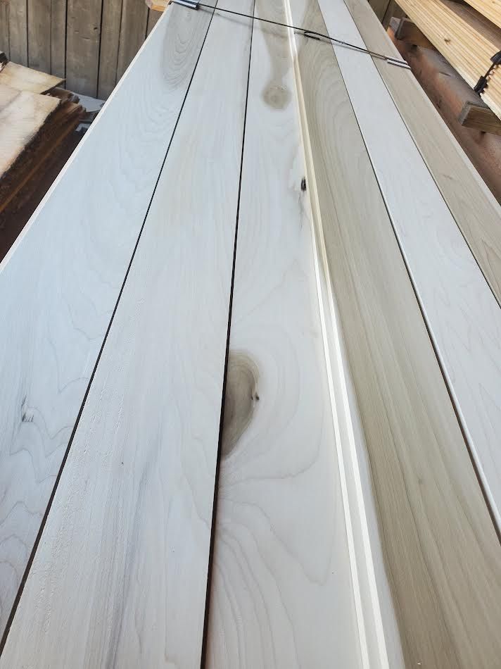 Several light-colored wooden planks stacked diagonally, revealing wood grain and some knots.