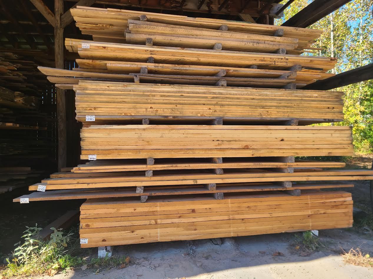 Stacks of wooden planks stored outdoors on metal supports.