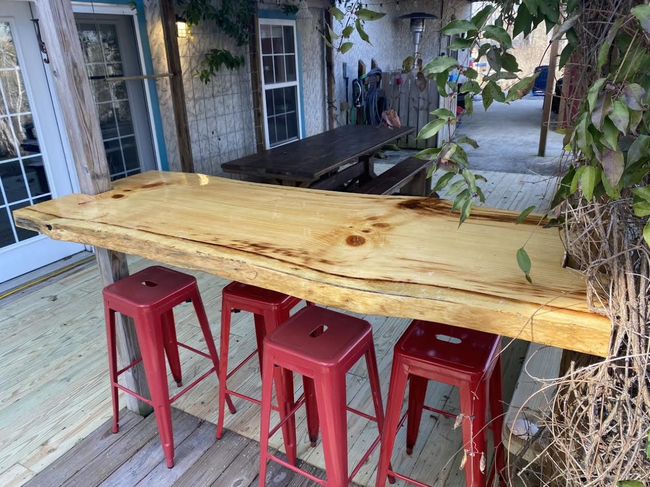 Outdoor bar with a wooden countertop and red stools.
