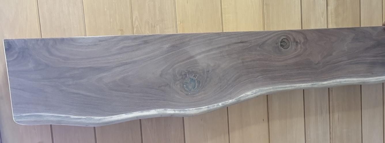 A dark wood slab with a natural edge lies on a light wooden background.