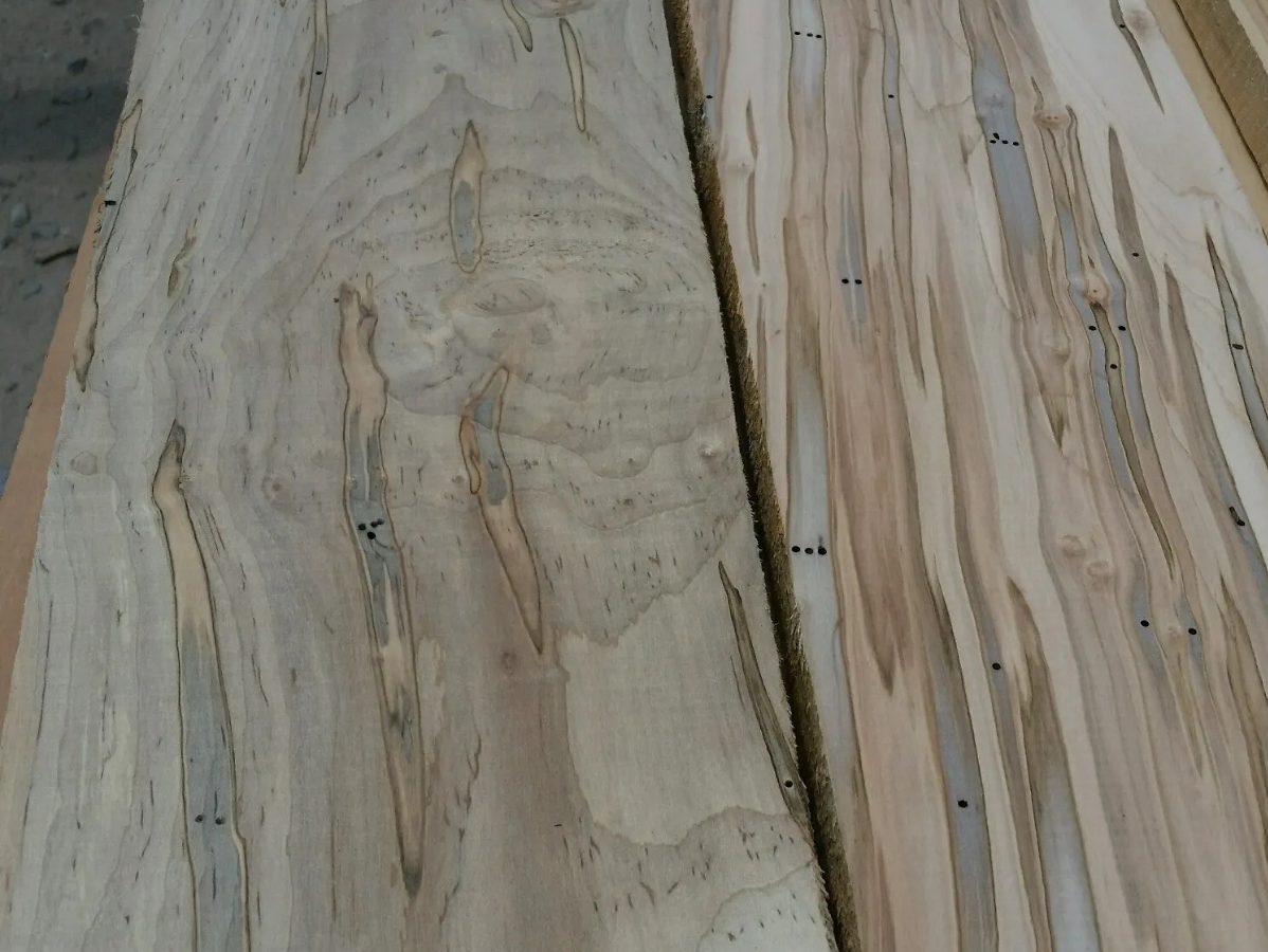 Close-up of two wooden planks showing swirling grain patterns, knots, and areas with blue-gray streaks.
