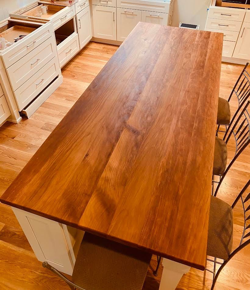 Wooden kitchen island with a light wooden floor and white cabinets.