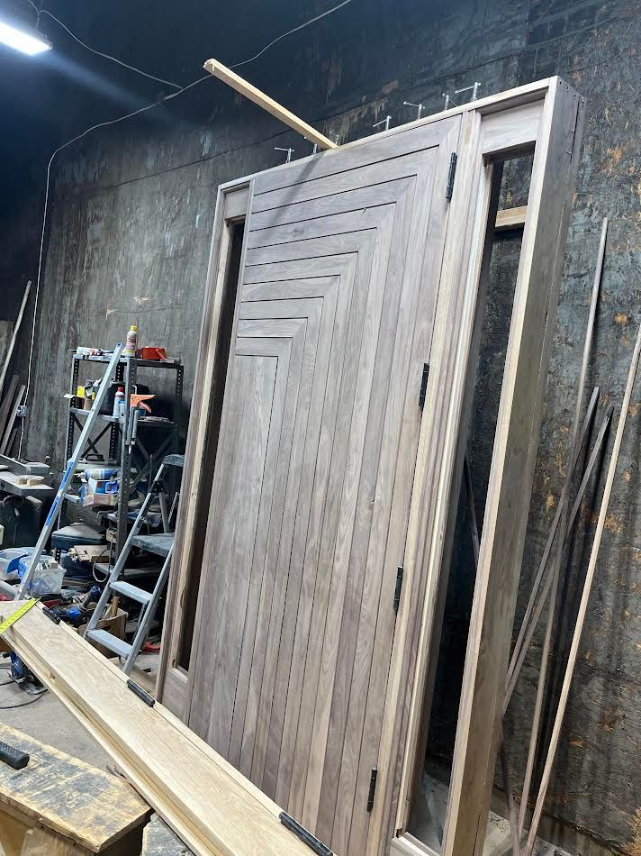 Wooden door with geometric design, leaning against a frame in a workshop.