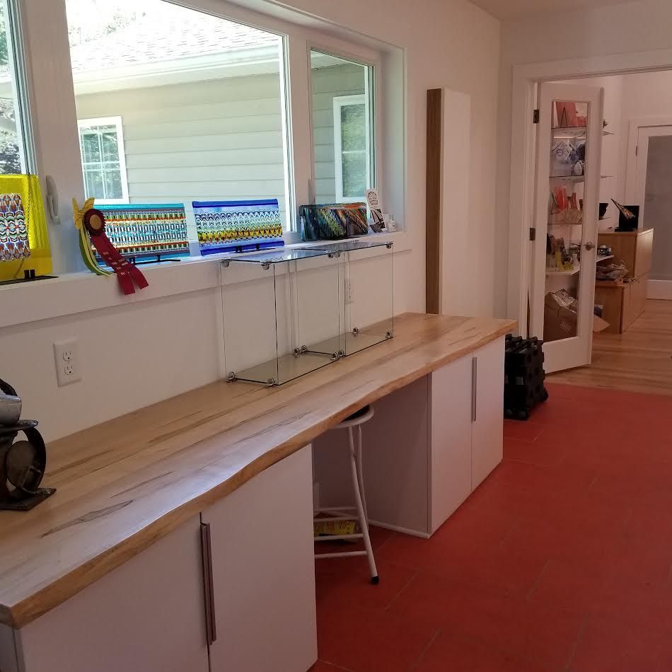 Workshop interior with white cabinets, wood countertop, red floor, window with glass art display.