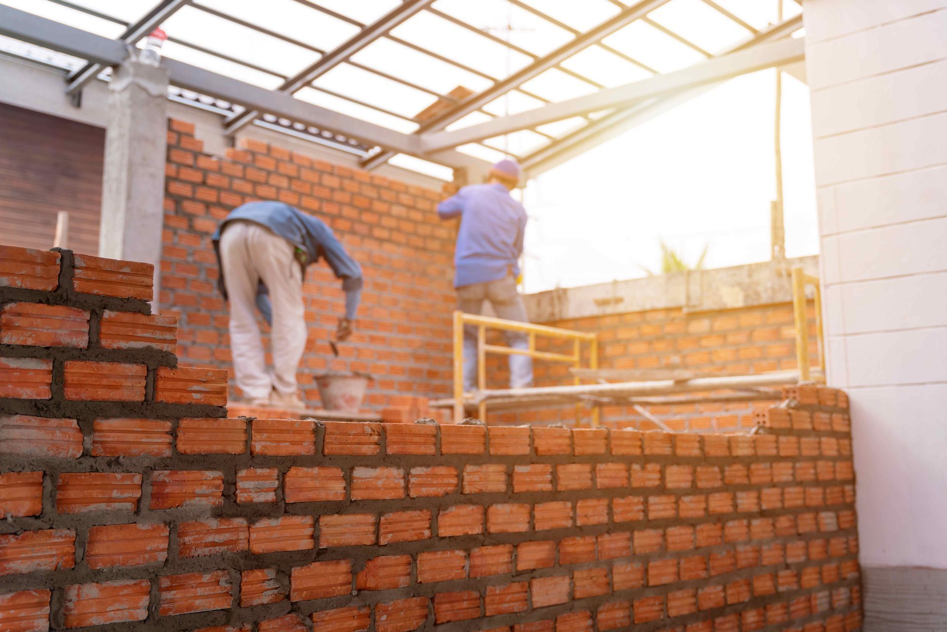 two construction workers are working on a brick wall