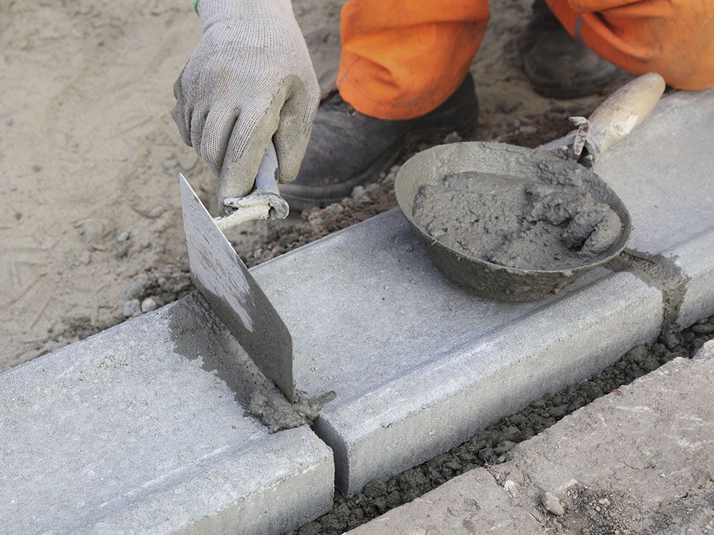 a person is using a trowel to spread concrete